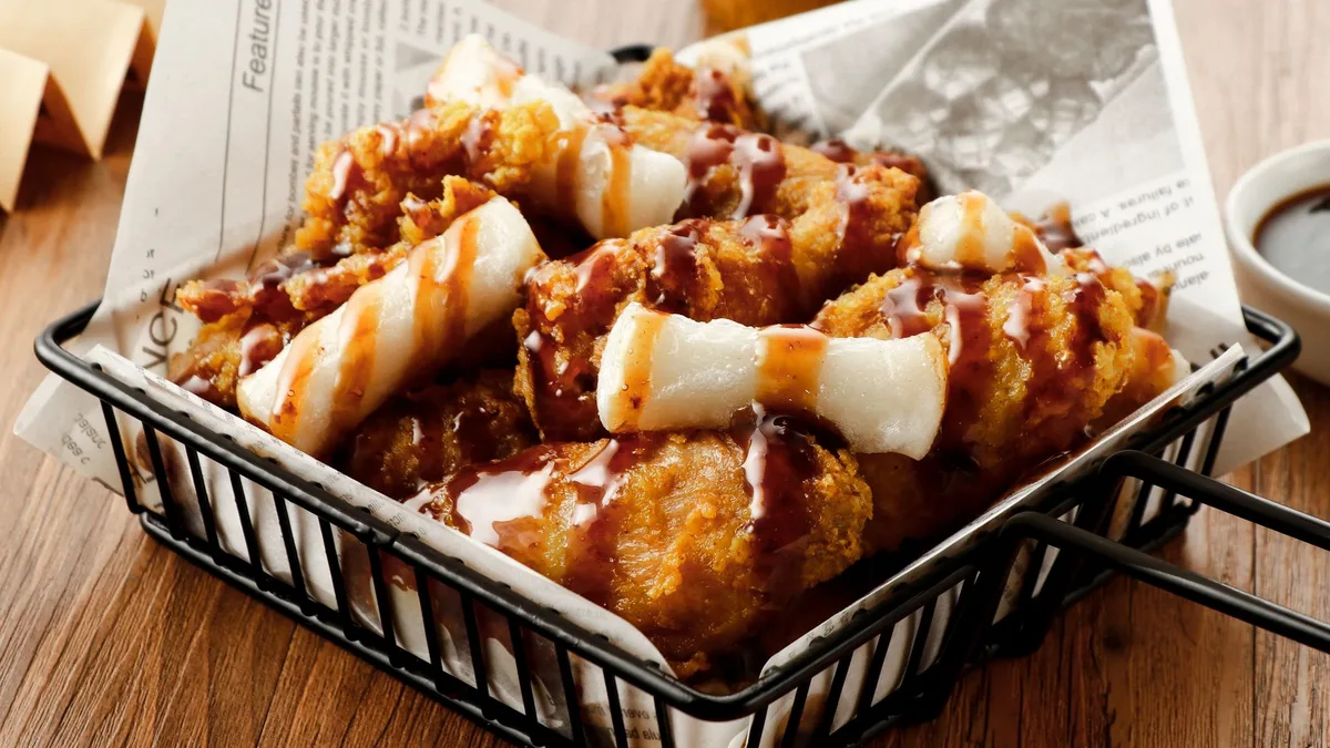 Loaded fries piled with cheese sauce and chicken bites — Dave's Hot Chicken Top-Loaded Fries