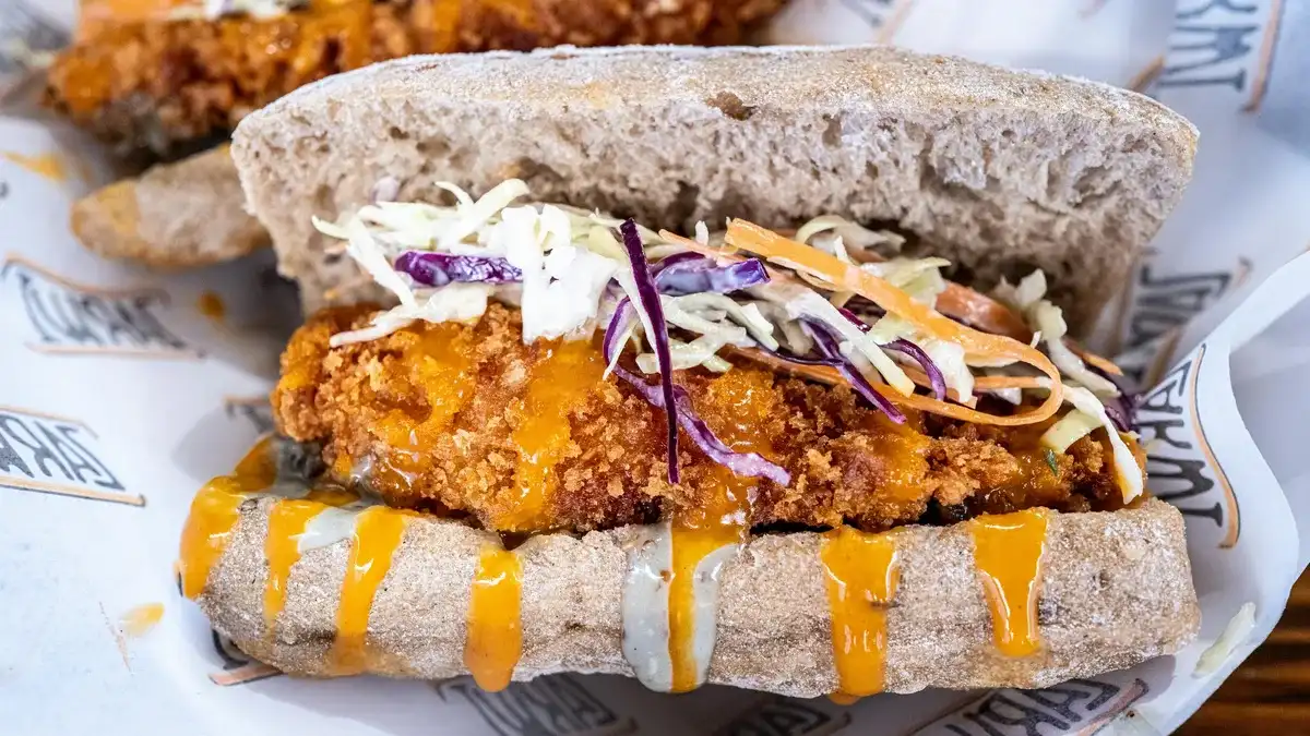 Crispy chicken slider topped with coleslaw and sauce next to fries — what's in a Dave's Hot Chicken order