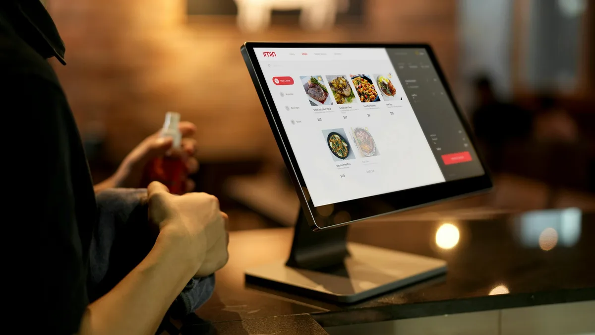 Customer using a self-order touchscreen at a fast-food counter — verifying halal status at the location