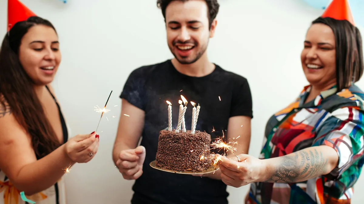 Friends celebrating a birthday with cake and sparklers — the Dave's Hot Chicken birthday reward
