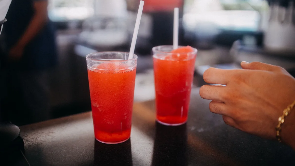 Two frozen fruit slushie drinks with straws — Dave's Hot Chicken Slusher flavors